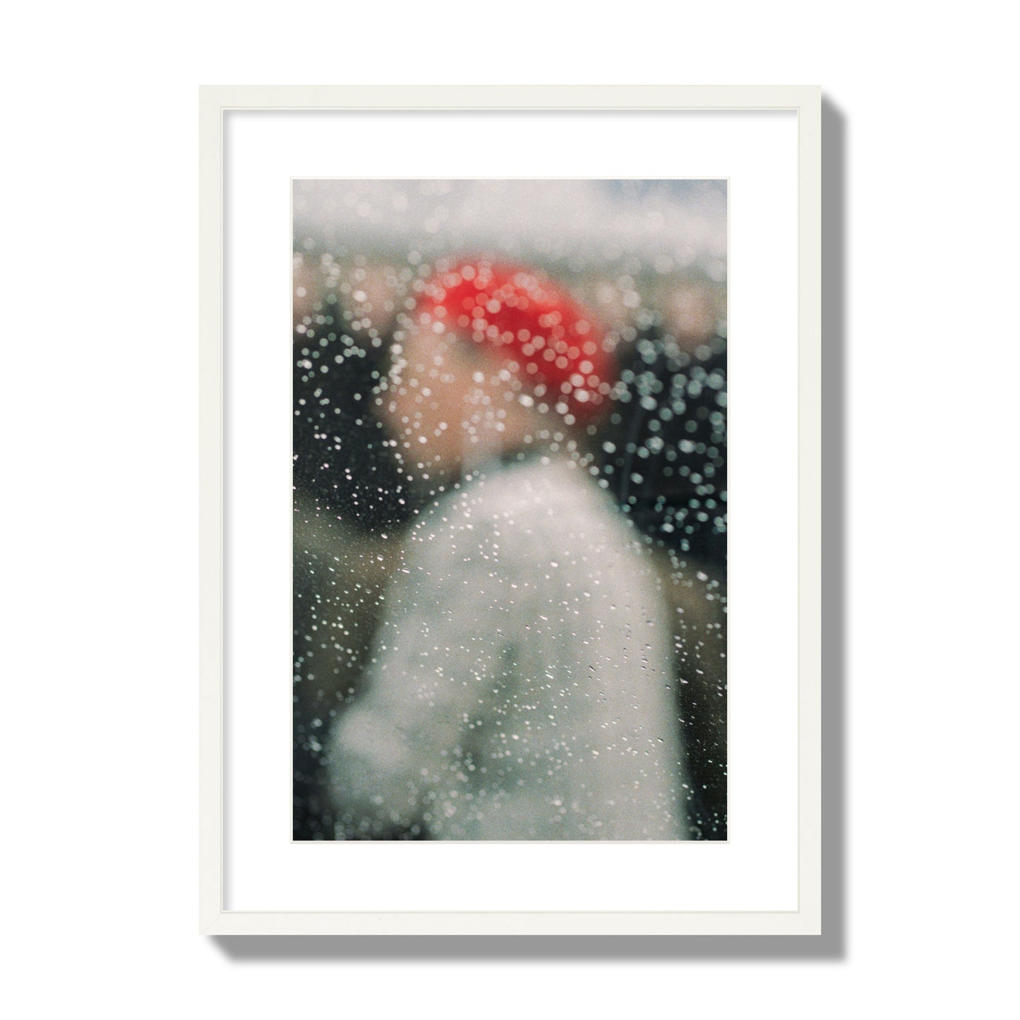 Fine art photograph of a woman with a red hat through raindrops on a window, archival pigment print, large size, white frame.