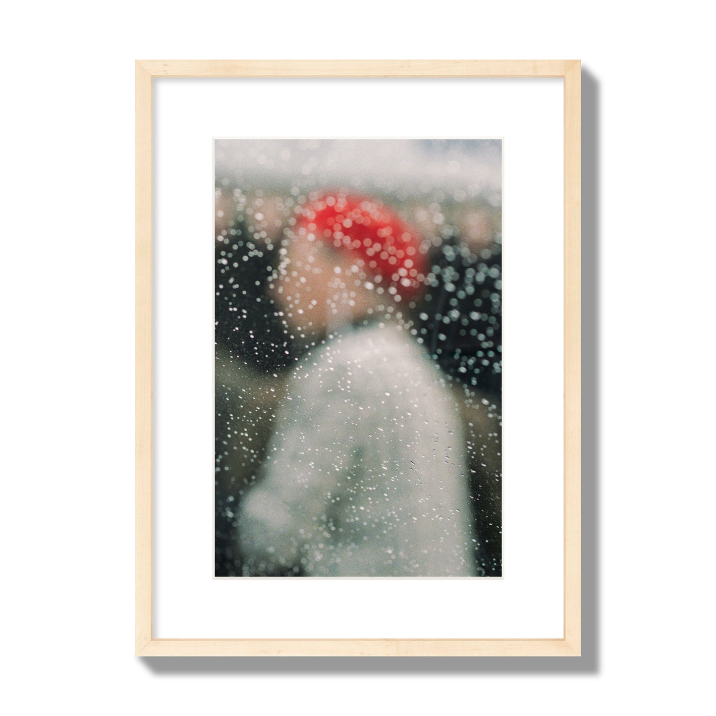 Fine art photograph of a woman with a red hat through raindrops on a window, archival pigment print, medium size, natural wood frame.