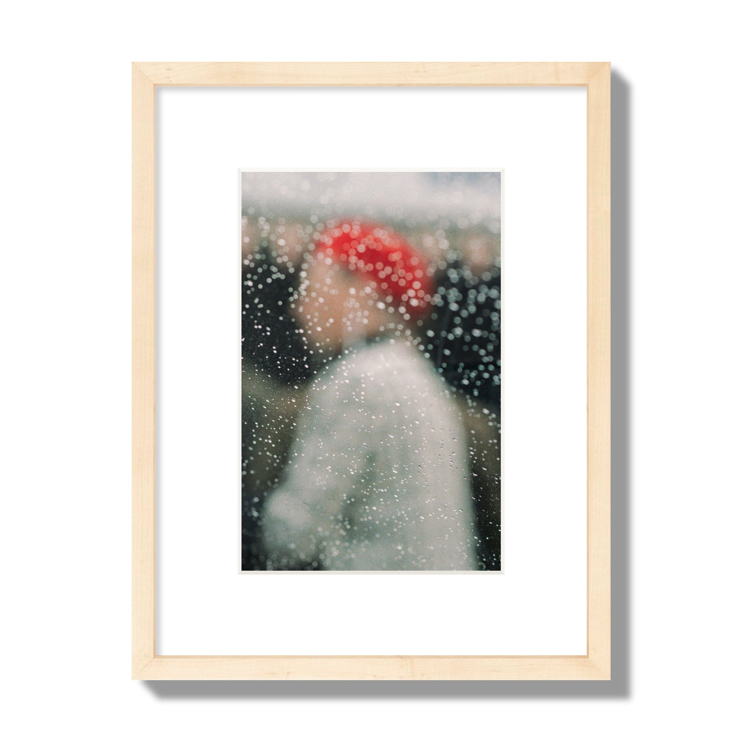 Fine art photograph of a woman with a red hat through raindrops on a window, archival pigment print, small size, natural wood frame.