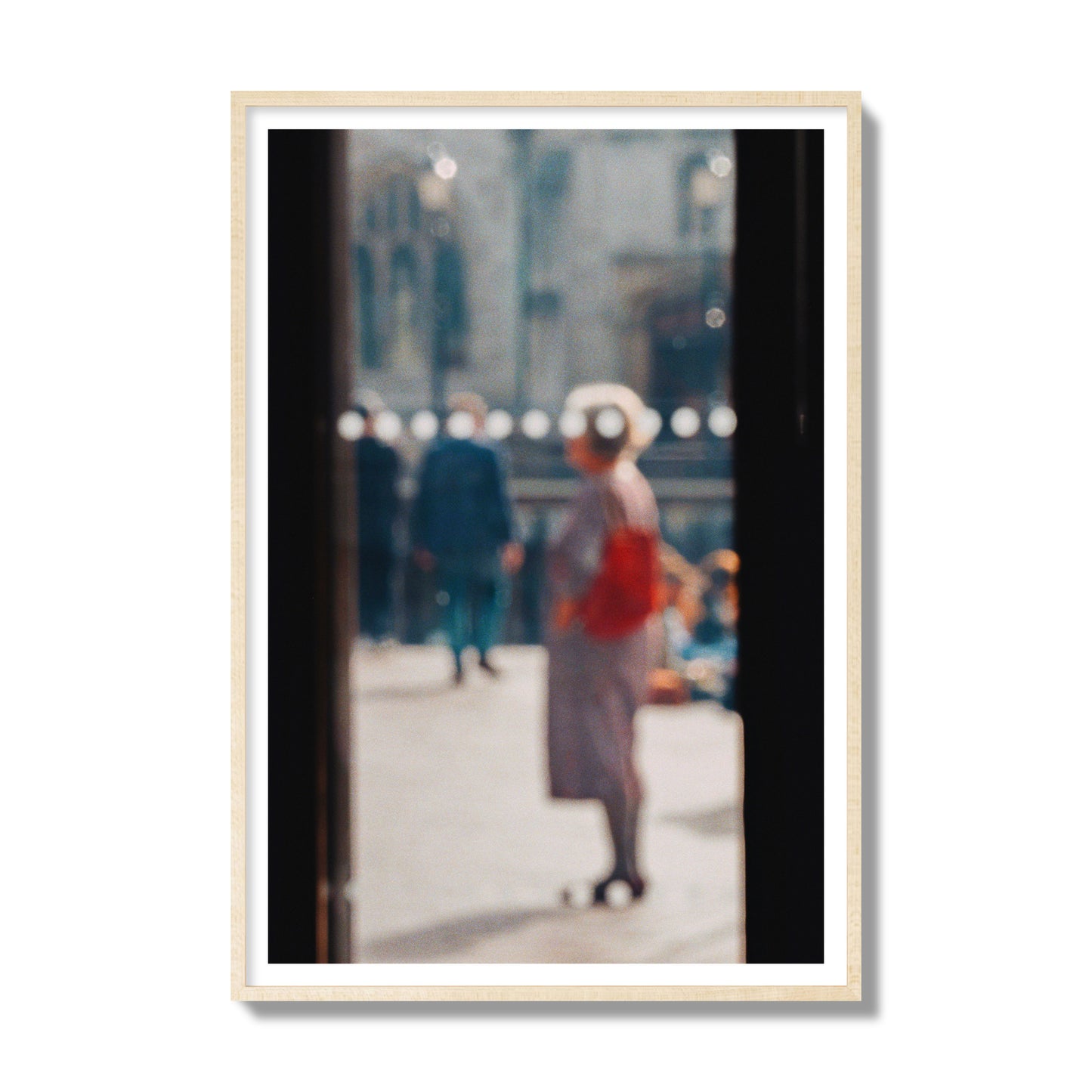 Fine art photograph of a blurred street scene with people and a storefront, archival pigment print, gallery size, natural wood frame.