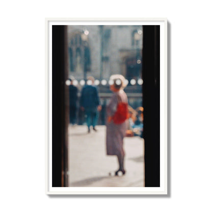 Fine art photograph of a blurred street scene with people and a storefront, archival pigment print, gallery size, white frame.