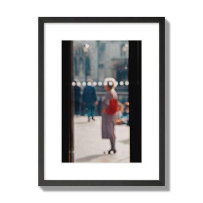 Fine art photograph of a blurred street scene with people and a storefront, archival pigment print, medium size, black frame.