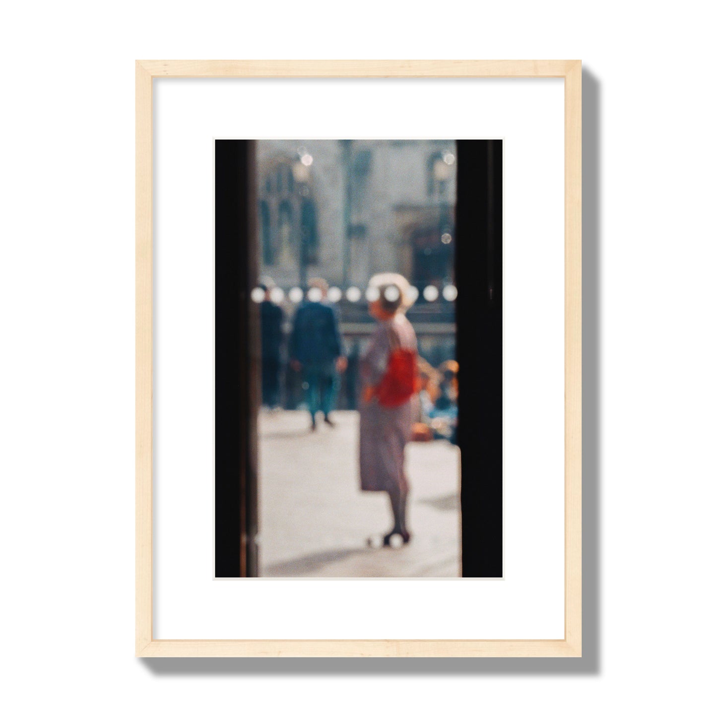 Fine art photograph of a blurred street scene with people and a storefront, archival pigment print, medium size, natural wood frame.