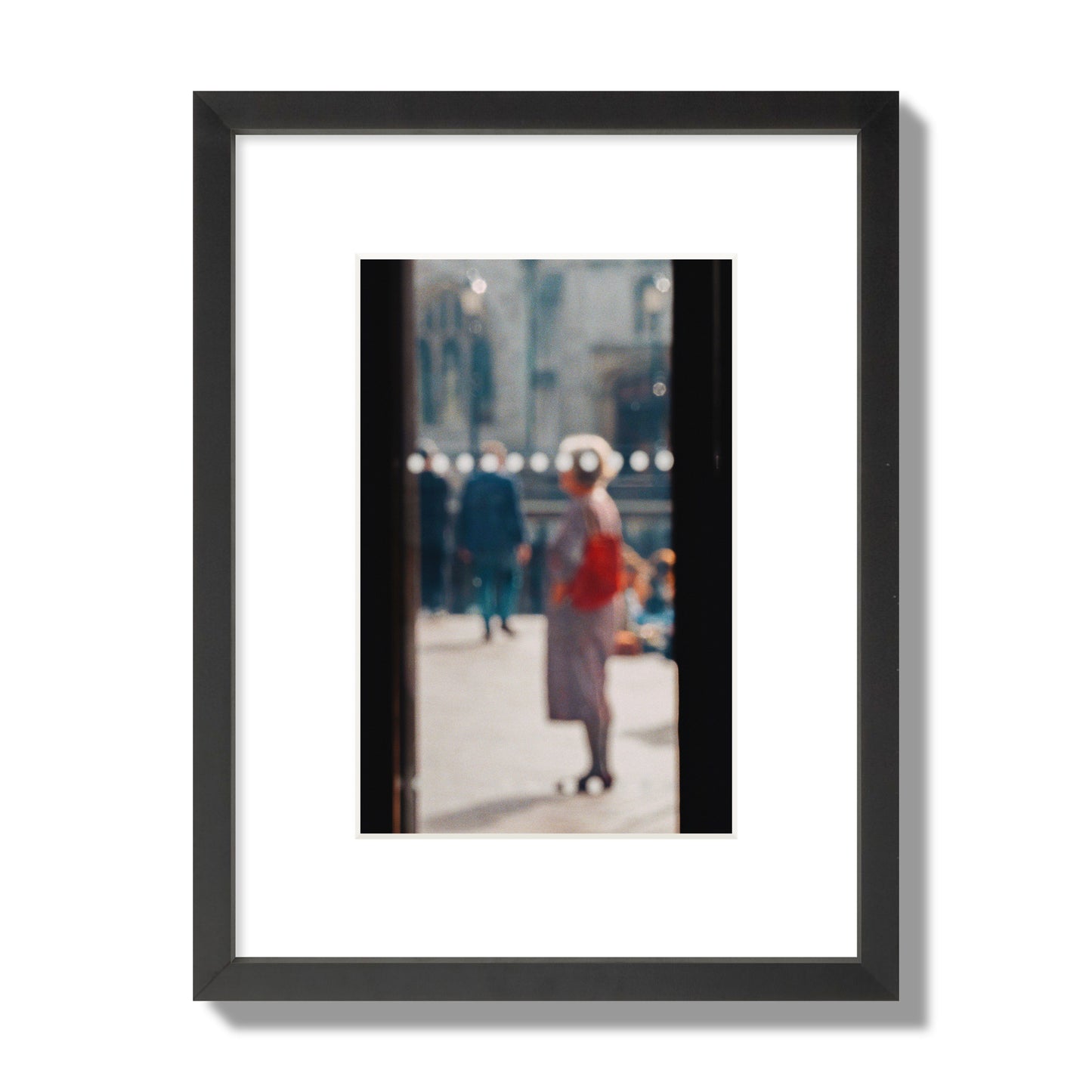 Fine art photograph of a blurred street scene with people and a storefront, archival pigment print, small size, black frame.