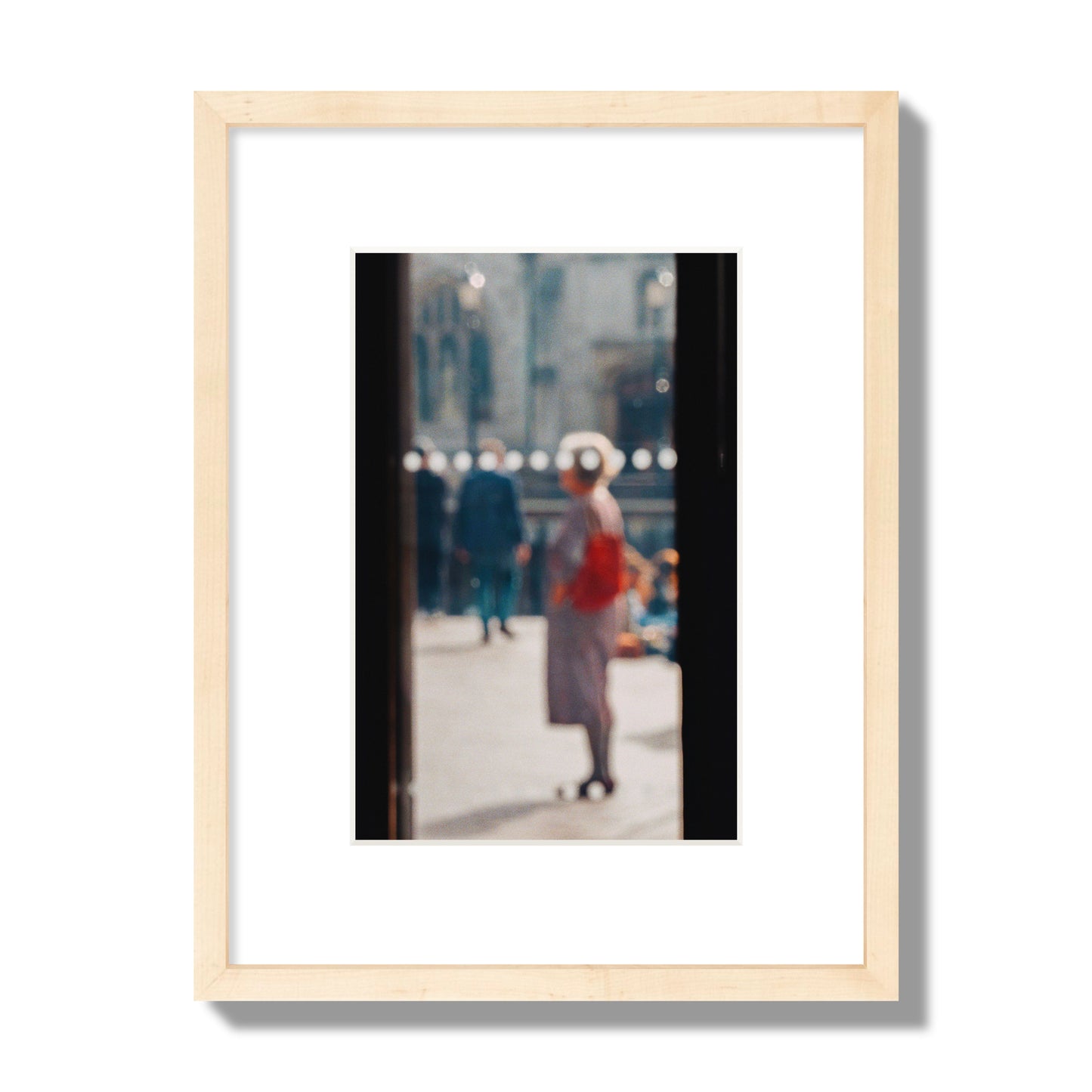 Fine art photograph of a blurred street scene with people and a storefront, archival pigment print, small size, natural wood frame.