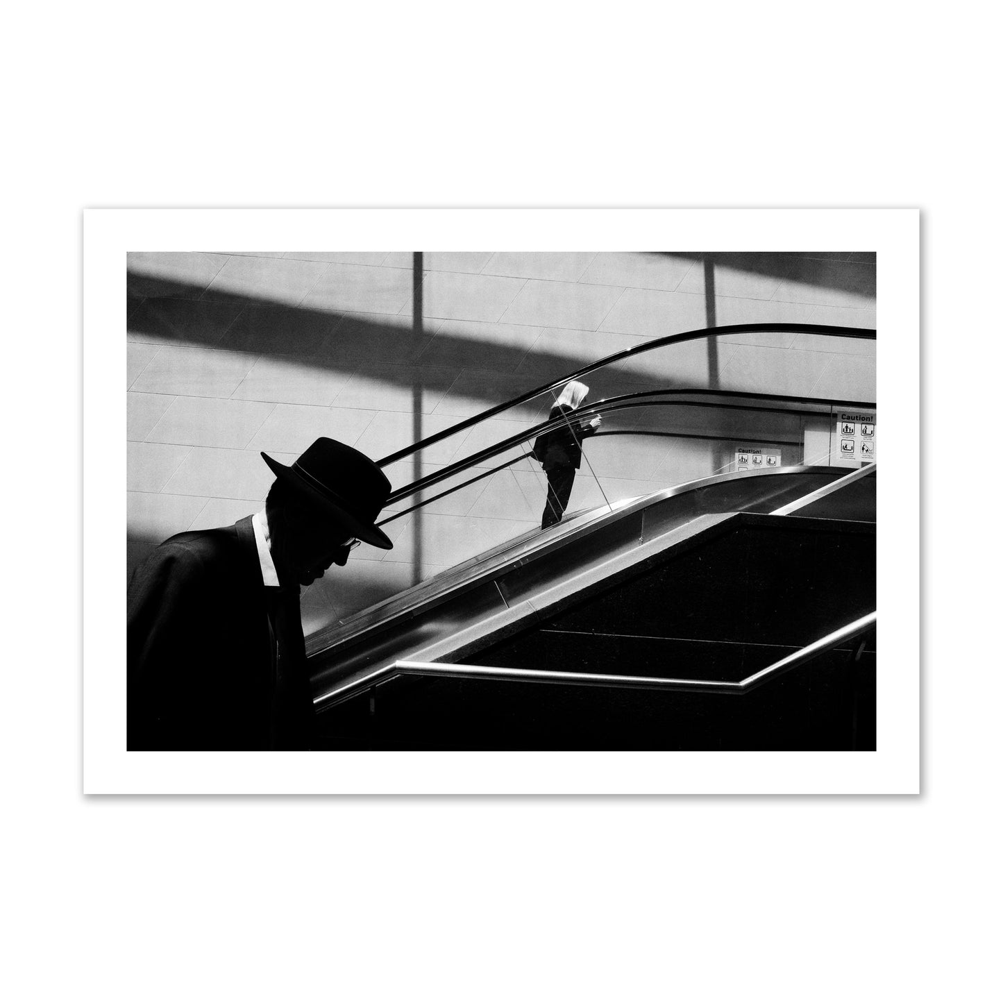 Fine art black and white street photograph of a man ascending an escalator. Archival pigment print, collector size, print.