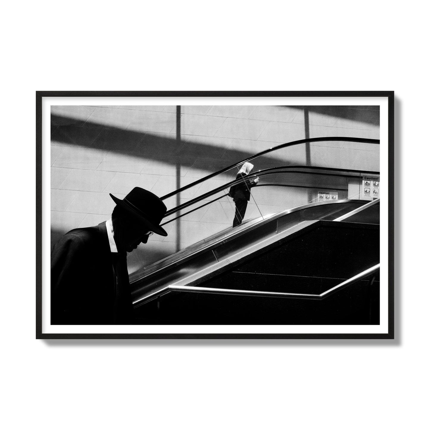 Fine art black and white street photograph of a man ascending an escalator. Archival pigment print, gallery size, black frame.