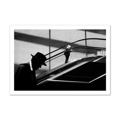 Fine art black and white street photograph of a man ascending an escalator. Archival pigment print, gallery size, print.