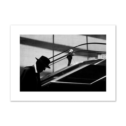 Fine art black and white street photograph of a man ascending an escalator. Archival pigment print, large size, print.