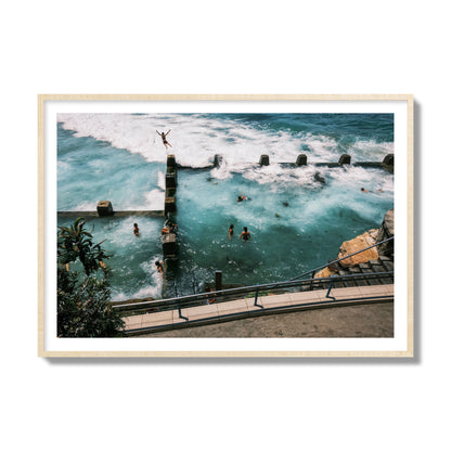 Fine art street photograph of a man jumping into the ocean. Archival pigment print, collector size, natural wood frame.