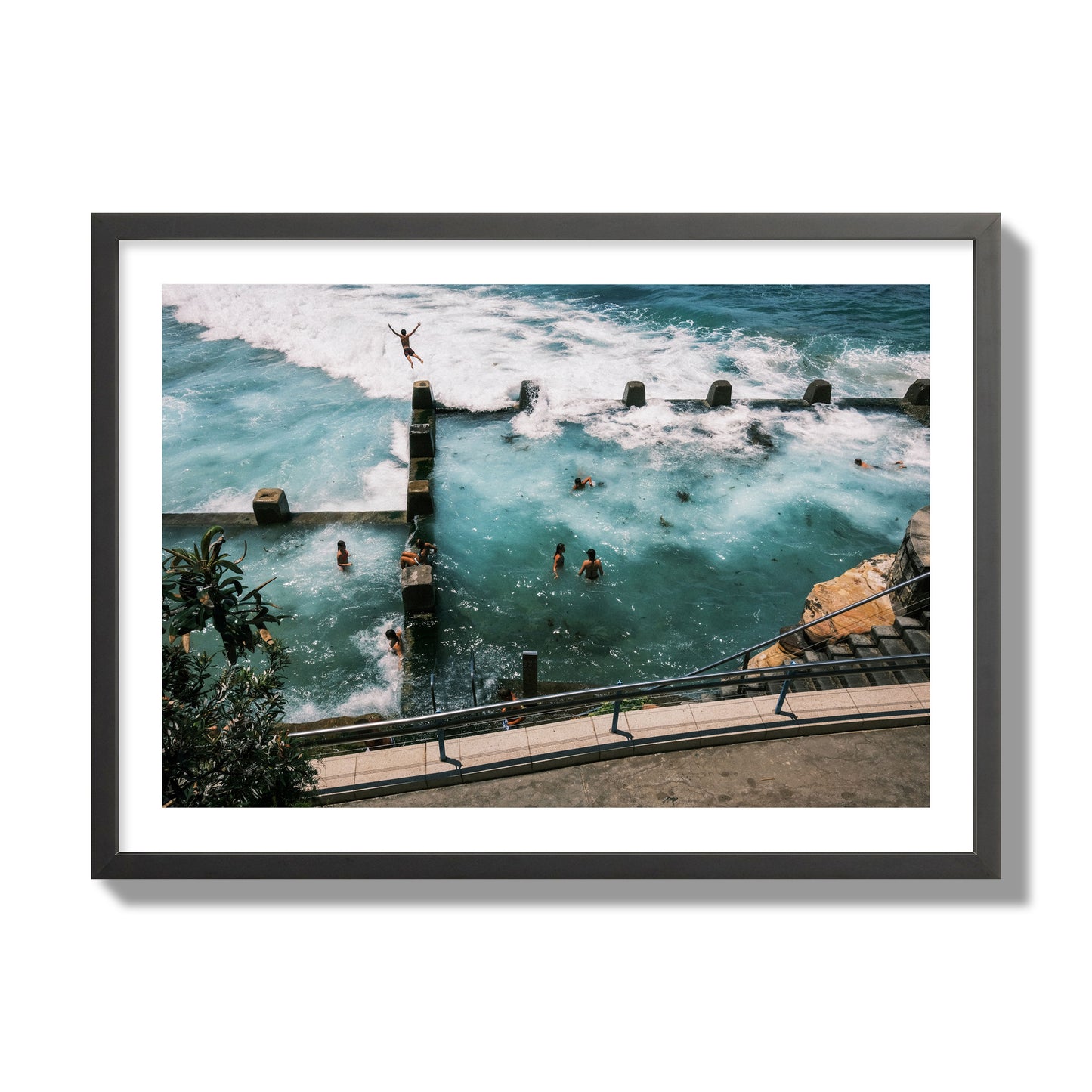 Fine art street photograph of a man jumping into the ocean. Archival pigment print, giant size, black frame.