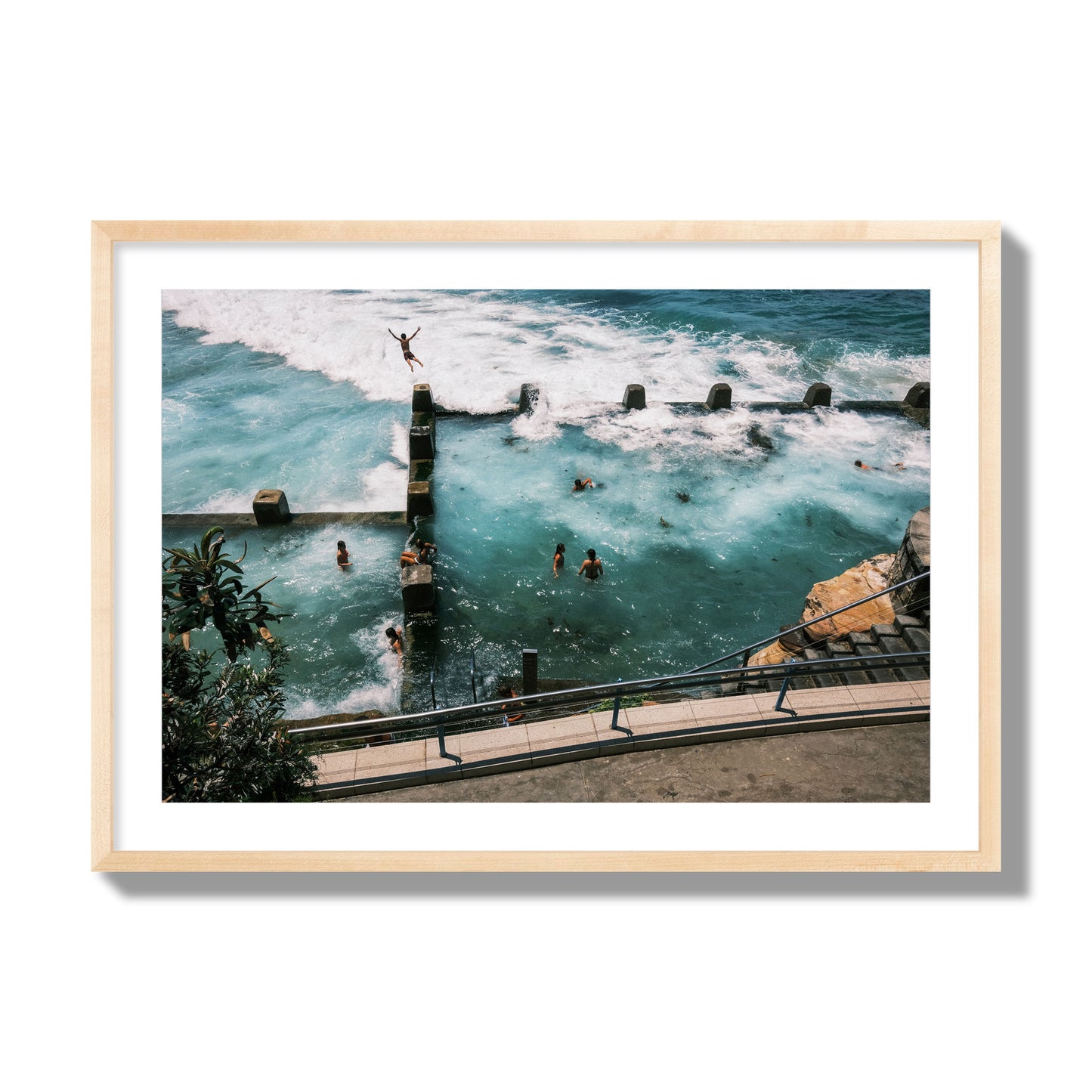 Fine art street photograph of a man jumping into the ocean. Archival pigment print, giant size, natural wood frame.