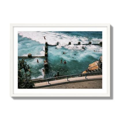 Fine art street photograph of a man jumping into the ocean. Archival pigment print, giant size, white frame.
