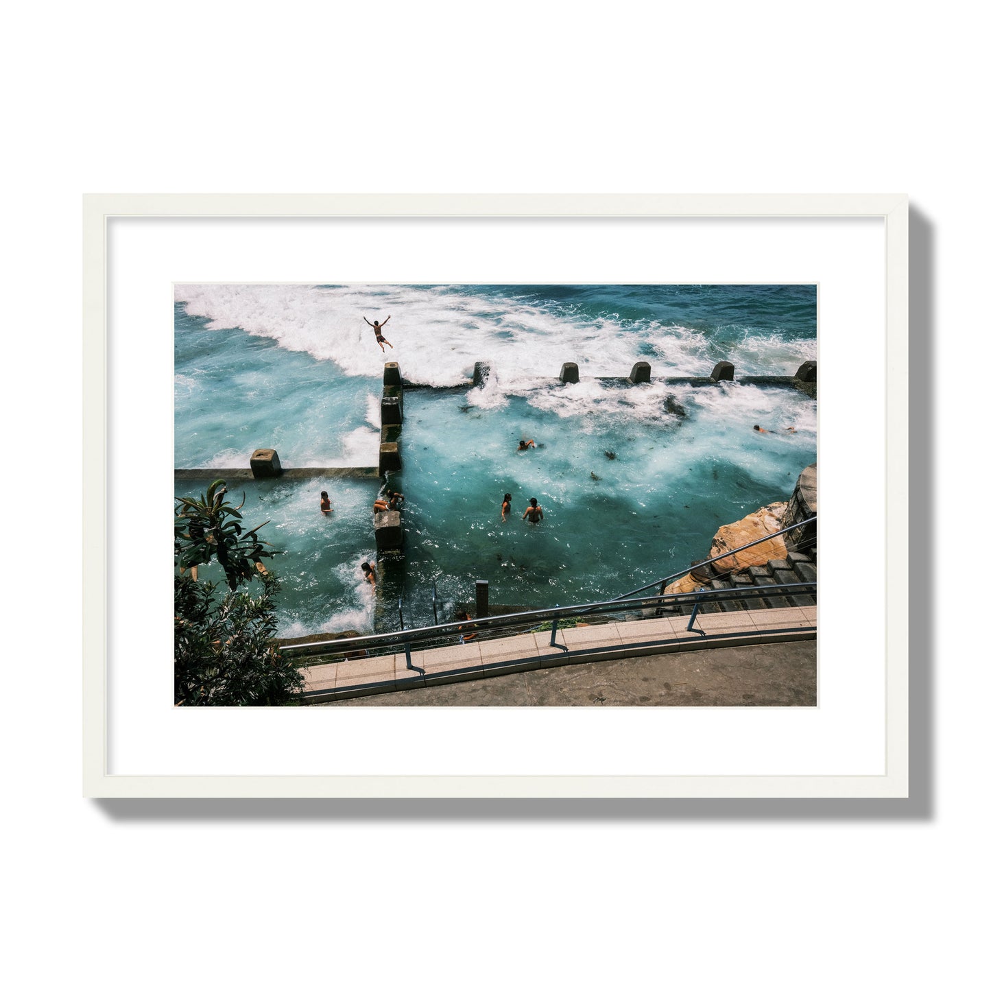 Fine art street photograph of a man jumping into the ocean. Archival pigment print, large size, white frame.