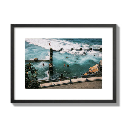 Fine art street photograph of a man jumping into the ocean. Archival pigment print, medium size, black frame.