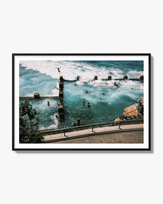 Fine art street photograph of a man jumping into the ocean. Archival pigment print, black frame.