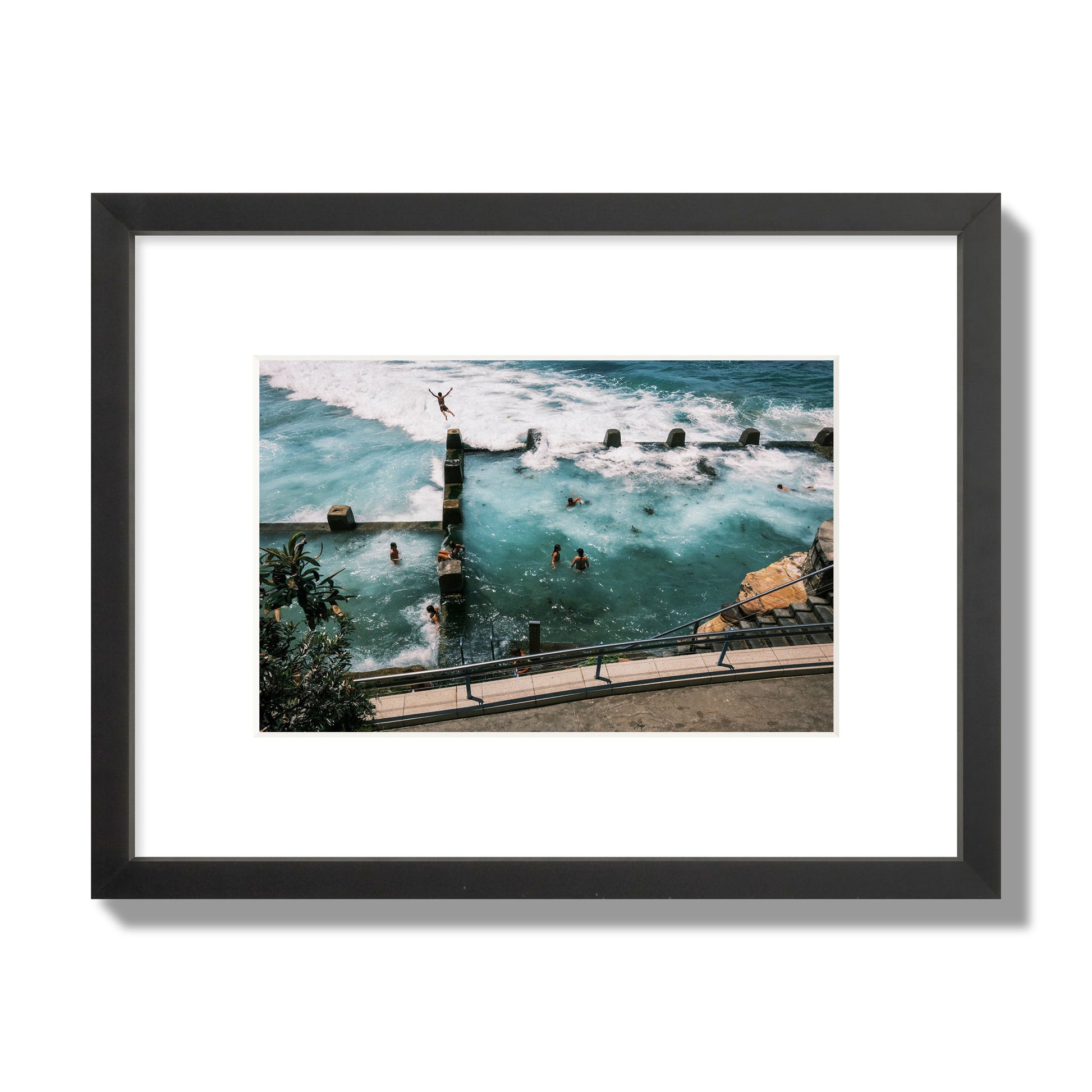 Fine art street photograph of a man jumping into the ocean. Archival pigment print, small size, black frame.
