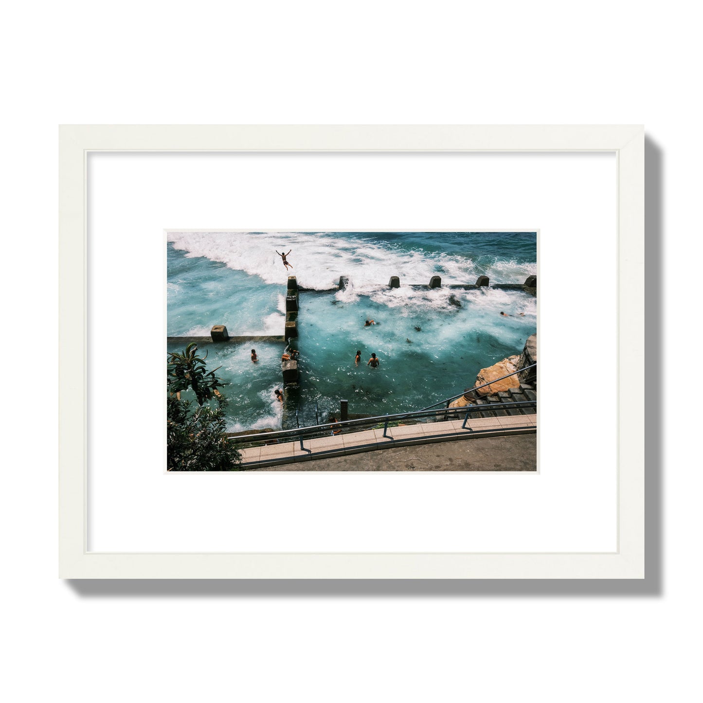 Fine art street photograph of a man jumping into the ocean. Archival pigment print, small size, white frame.