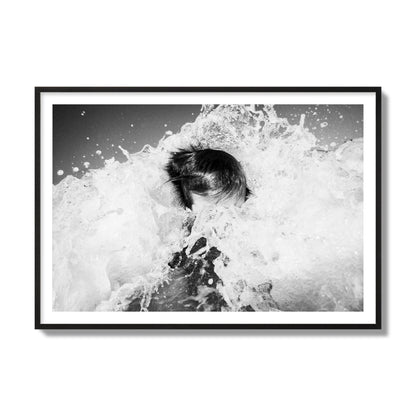 Fine art street photograph of an ocean wave crashing over a swimmer. Archival pigment print, collector size, black frame.