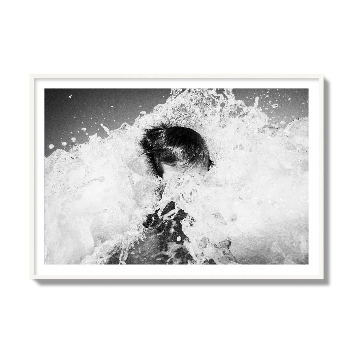 Fine art street photograph of an ocean wave crashing over a swimmer. Archival pigment print, collector size, white frame.