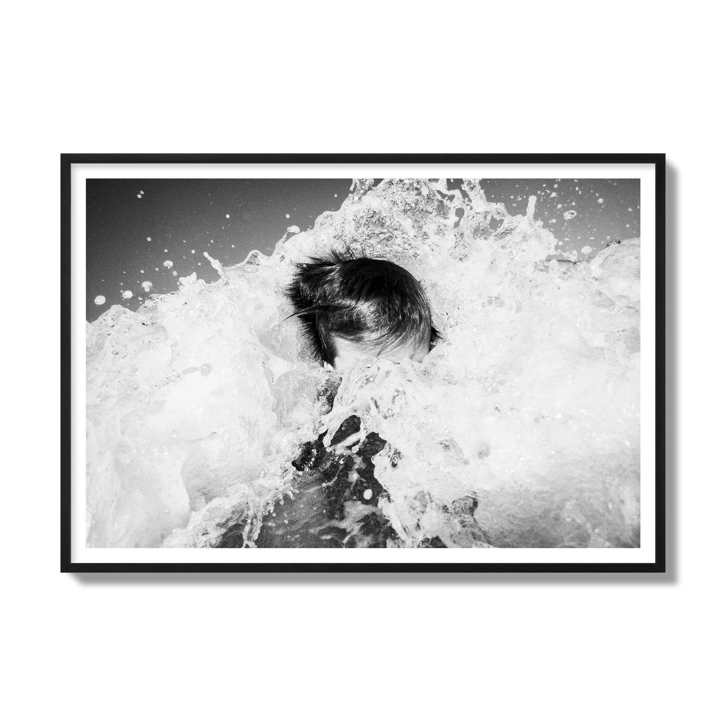 Fine art street photograph of an ocean wave crashing over a swimmer. Archival pigment print, gallery size, black frame.