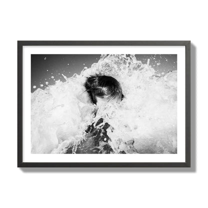 Fine art street photograph of an ocean wave crashing over a swimmer. Archival pigment print, giant size, black frame.