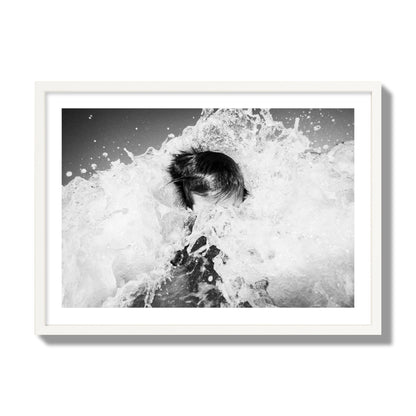 Fine art street photograph of an ocean wave crashing over a swimmer. Archival pigment print, giant size, white frame.