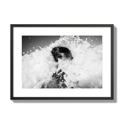 Fine art street photograph of an ocean wave crashing over a swimmer. Archival pigment print, large size, black frame.