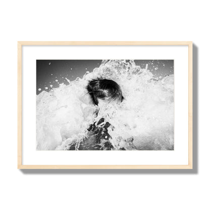 Fine art street photograph of an ocean wave crashing over a swimmer. Archival pigment print, large size, natural wood frame.