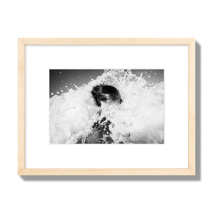 Fine art street photograph of an ocean wave crashing over a swimmer. Archival pigment print, small size, natural wood frame.