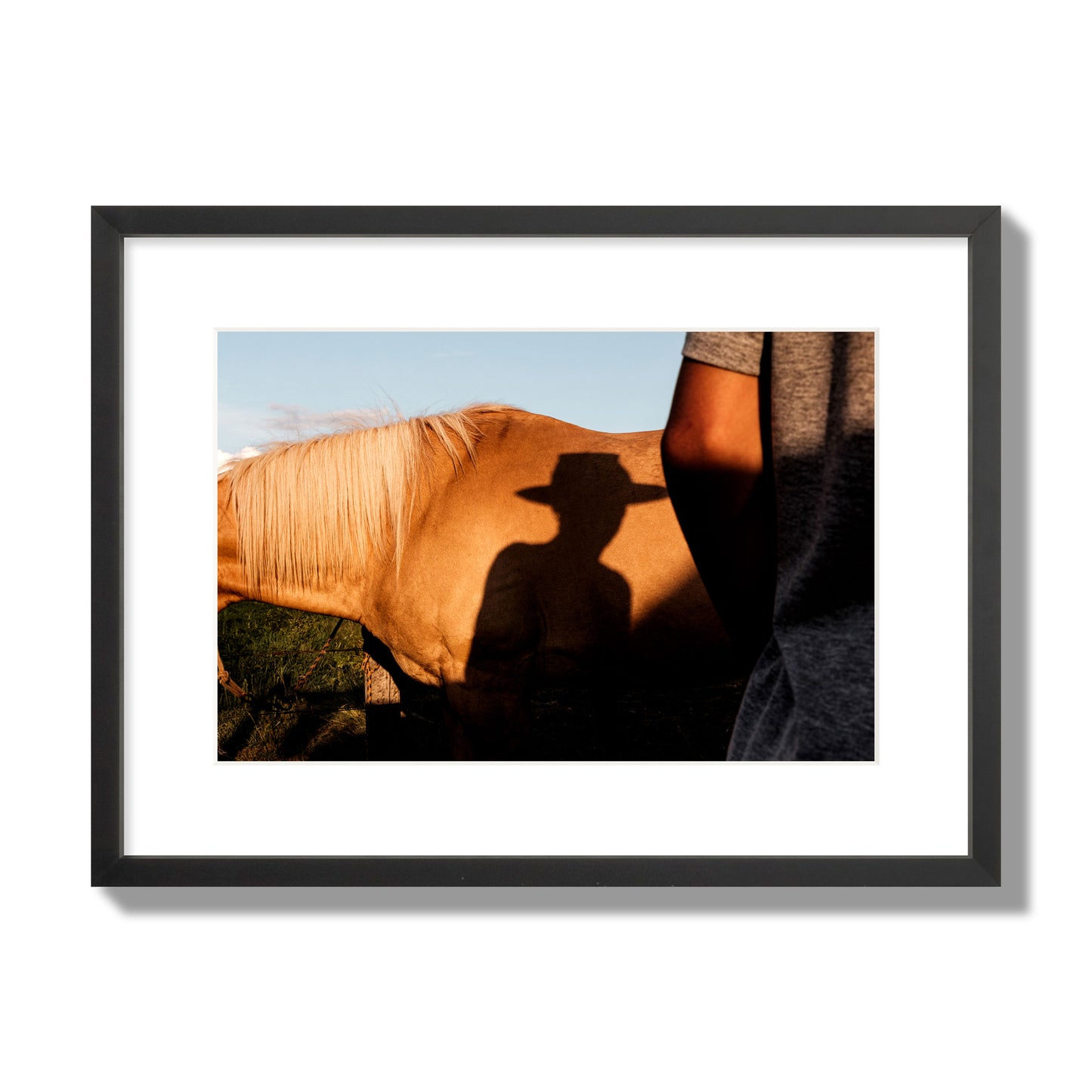 Fine art photo of a cowboy's shadow cast against the side of a horse at sunset. Archival pigment print, medium size, black frame.