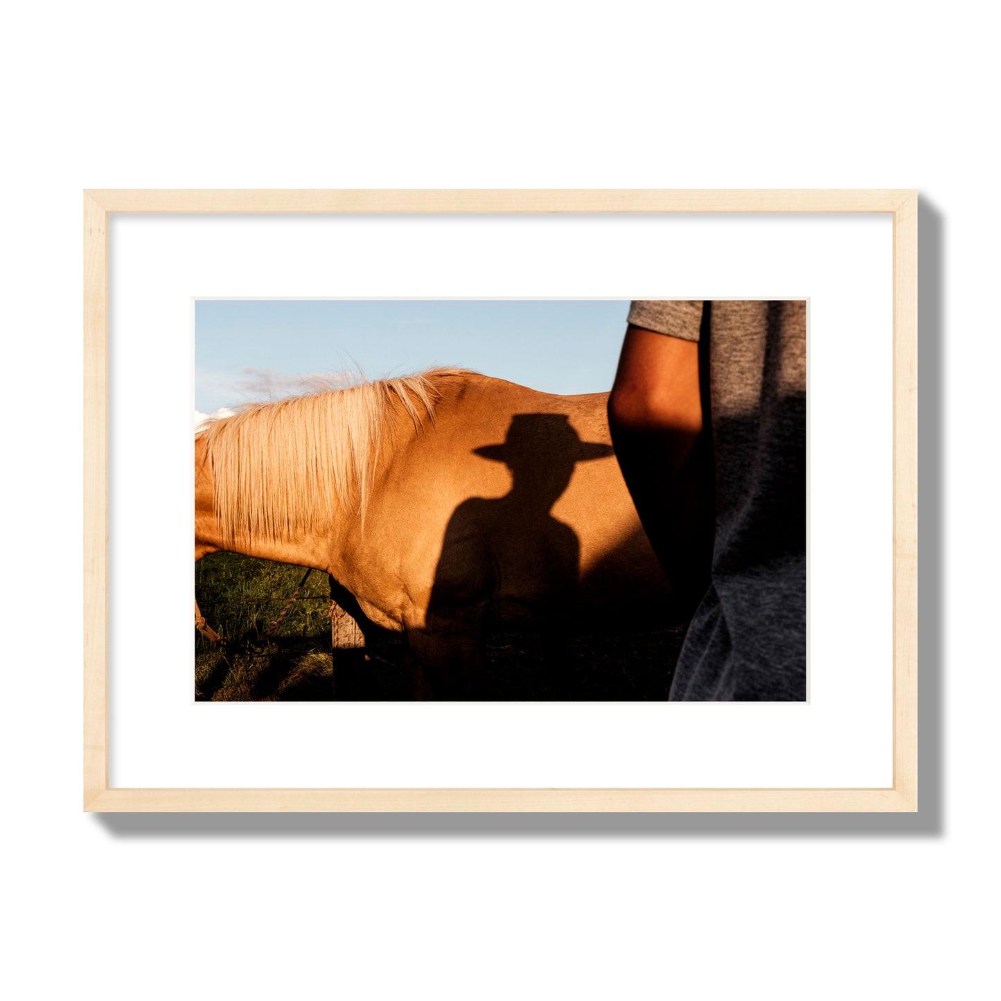 Fine art photo of a cowboy's shadow cast against the side of a horse at sunset. Archival pigment print, medium size, natural wood frame.