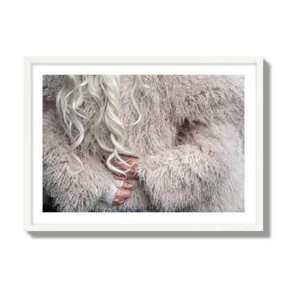 Fine art  street photograph of a woman wrapped in a huge furry coat. Archival pigment print, giant size, white frame.