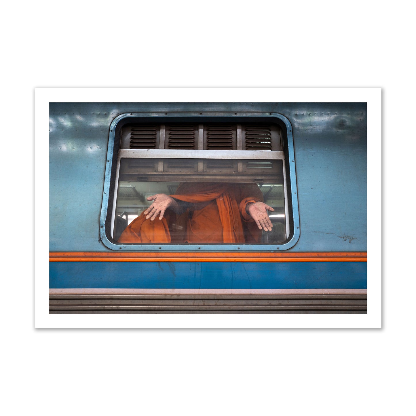Fine art photograph of a Buddhist monk standing with open hands at a train car window. Archival pigment print, gallery size, print.
