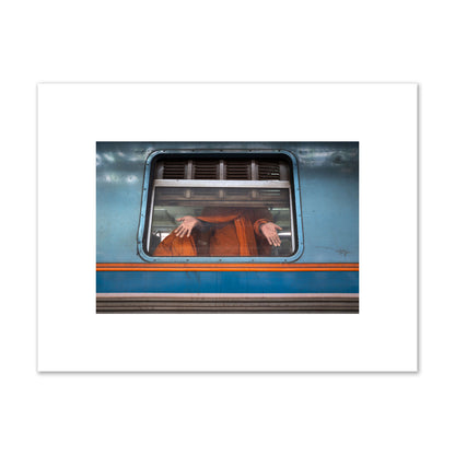 Fine art photograph of a Buddhist monk standing with open hands at a train car window. Archival pigment print, small size, print.