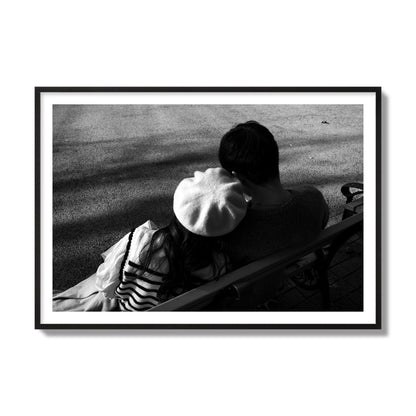 Fine art black and white street photograph of a romantic couple cuddling on a park bench. Archival pigment print, collector size, black frame.
