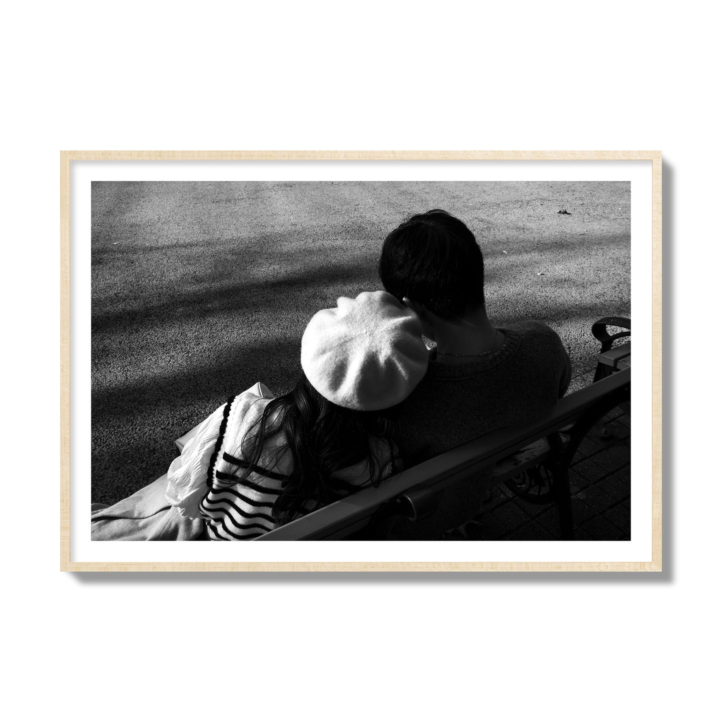 Fine art black and white street photograph of a romantic couple cuddling on a park bench. Archival pigment print, collector size, natural wood frame.