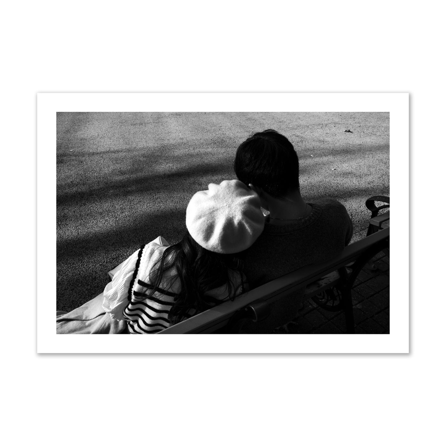 Fine art black and white street photograph of a romantic couple cuddling on a park bench. Archival pigment print, collector size, print.