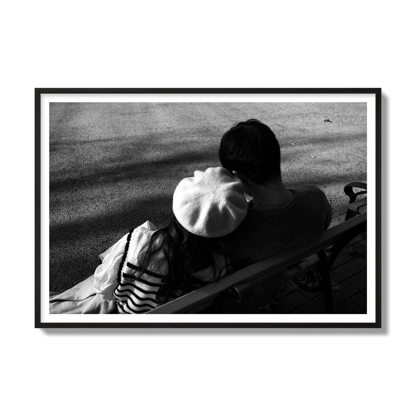 Fine art black and white street photograph of a romantic couple cuddling on a park bench. Archival pigment print, gallery size, black frame.