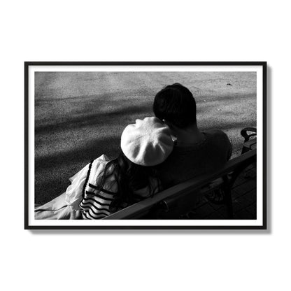 Fine art black and white street photograph of a romantic couple cuddling on a park bench. Archival pigment print, gallery size, black frame.