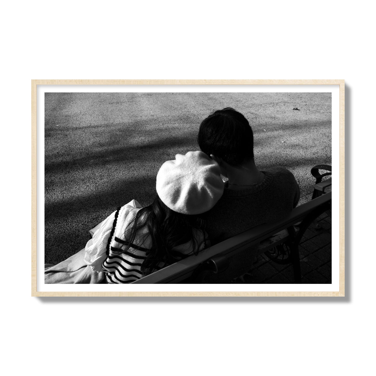 Fine art black and white street photograph of a romantic couple cuddling on a park bench. Archival pigment print, gallery size, natural wood frame.