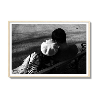 Fine art black and white street photograph of a romantic couple cuddling on a park bench. Archival pigment print, gallery size, natural wood frame.