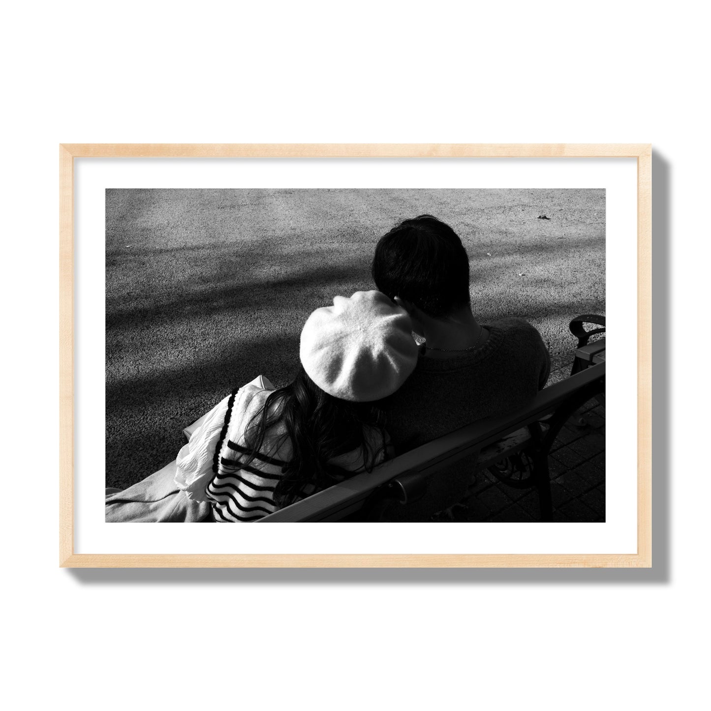 Fine art black and white street photograph of a romantic couple cuddling on a park bench. Archival pigment print, giant size, natural wood frame.
