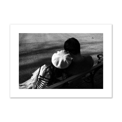 Fine art black and white street photograph of a romantic couple cuddling on a park bench. Archival pigment print, giant size, print.