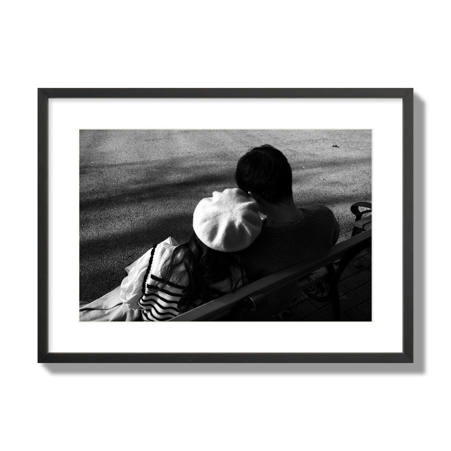 Fine art black and white street photograph of a romantic couple cuddling on a park bench. Archival pigment print, large size, black frame.