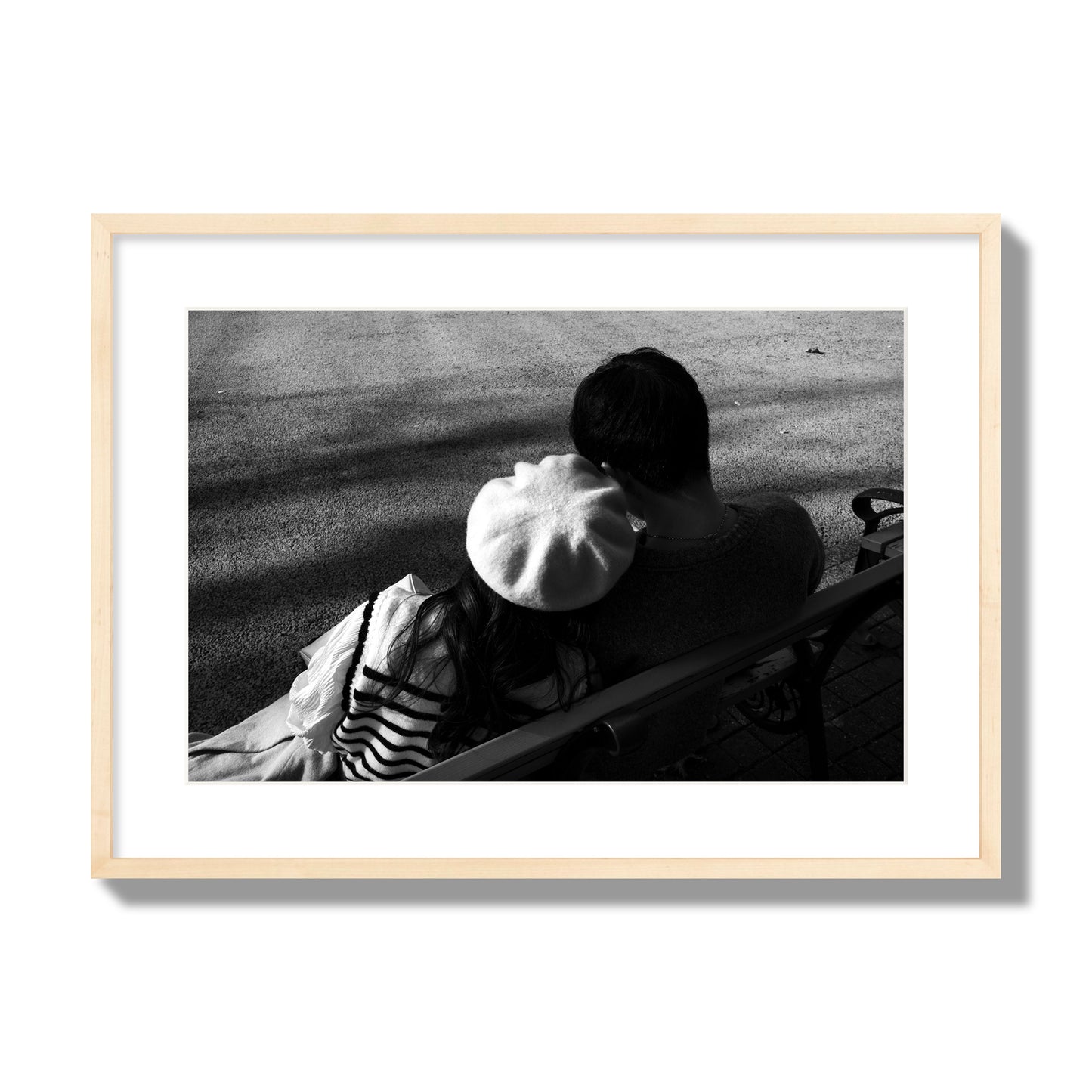 Fine art black and white street photograph of a romantic couple cuddling on a park bench. Archival pigment print, large size, natural wood frame.