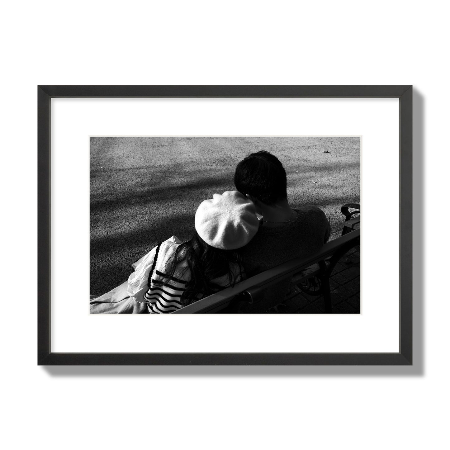 Fine art black and white street photograph of a romantic couple cuddling on a park bench. Archival pigment print, medium size, black frame.