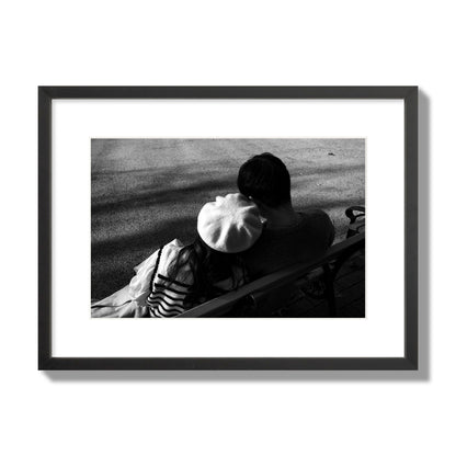 Fine art black and white street photograph of a romantic couple cuddling on a park bench. Archival pigment print, medium size, black frame.