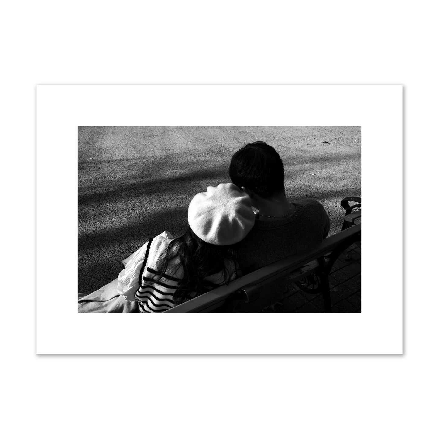 Fine art black and white street photograph of a romantic couple cuddling on a park bench. Archival pigment print, medium size, print.