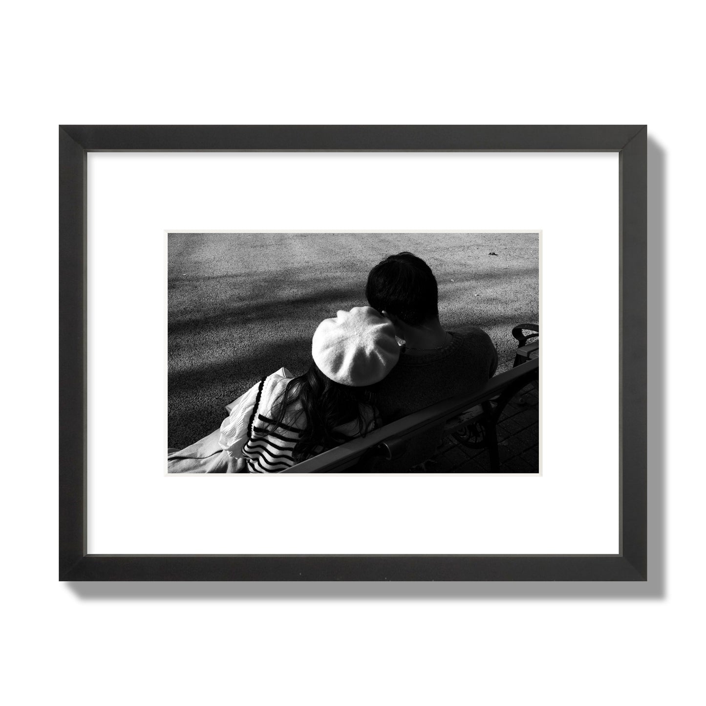 Fine art black and white street photograph of a romantic couple cuddling on a park bench. Archival pigment print, small size, black frame.
